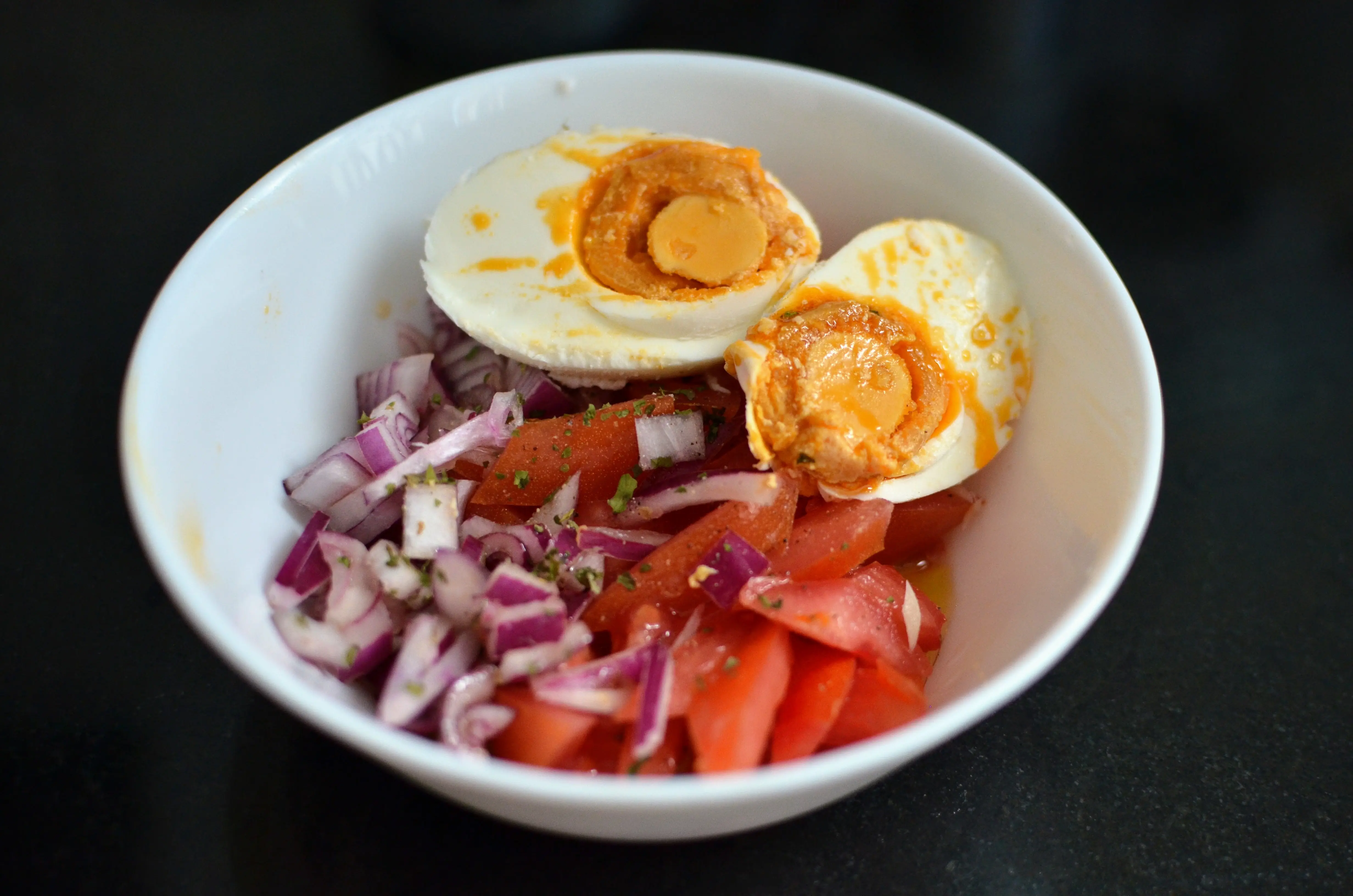 Salted egg halves nestled on a bed of tomato-onion ensalada